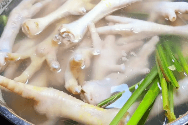 Chân gà làm sạch, cắt móng, luộc cùng gừng & sả cho dậy mùi